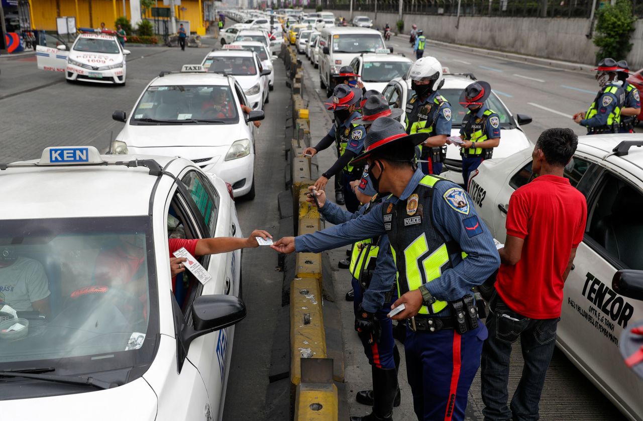 A taxi driver shows his ID and car documents to police who instructed them to stop operations while the government implements the "enhanced community quarantine" as a precautionary measure against the spread of the new coronavirus in Manila, Philippines on March 17.