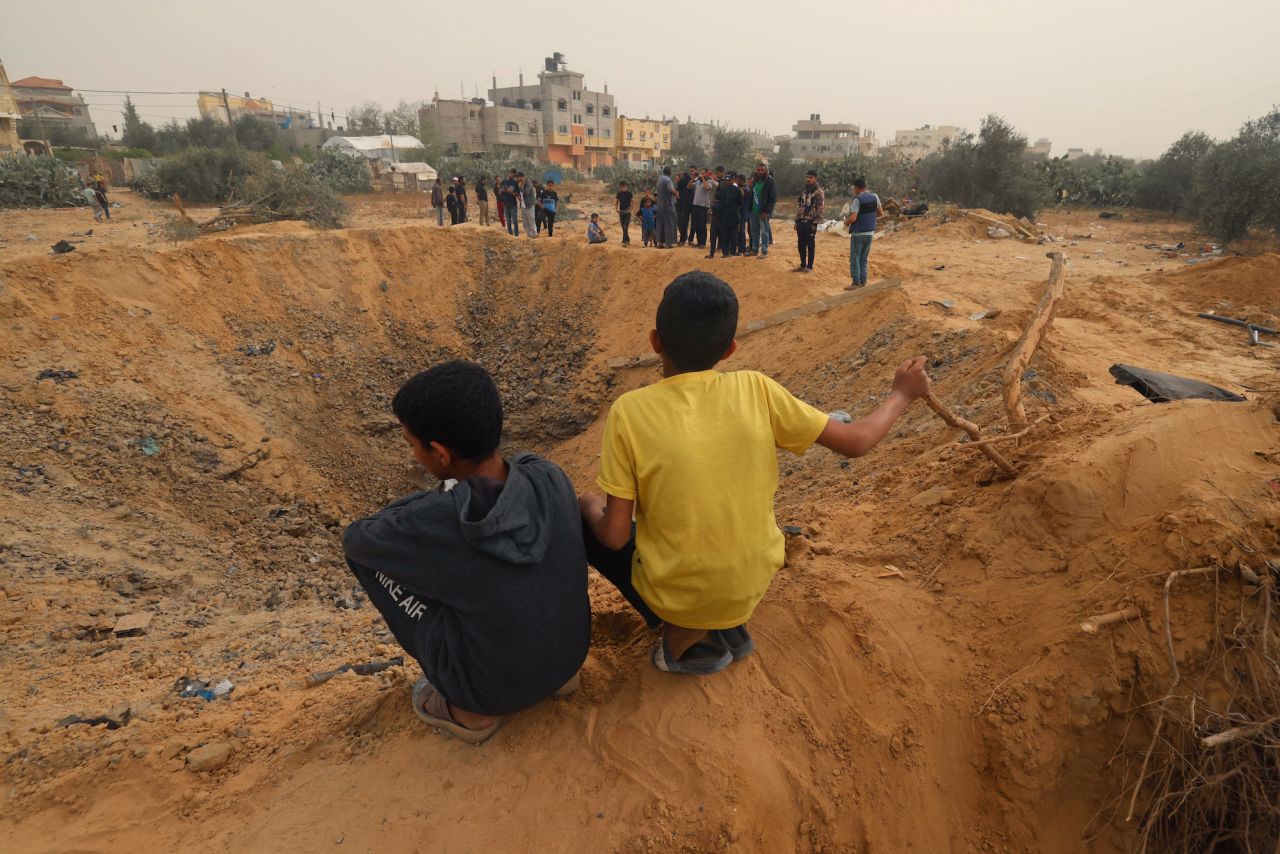 Two Palestinian boys are seen in front of a crater following overnight Israeli bombardment in Rafah, southern Gaza, on Thursday.
