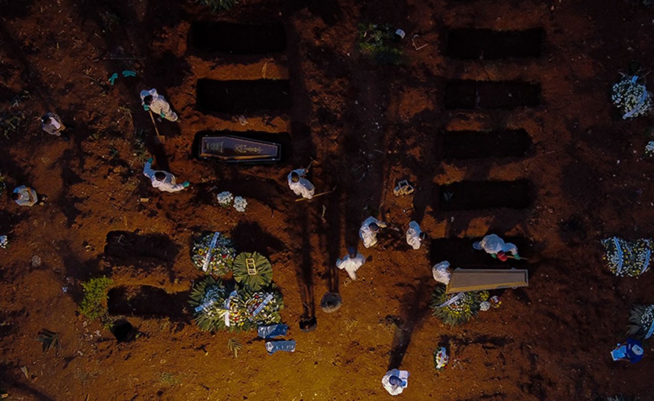 Workers in protective gear as a preventive measure against the spread of the novel coronavirus disease bury coffins at the Vila Formosa cemetery in Sao Paulo, Brazil, on April 17, 2021.