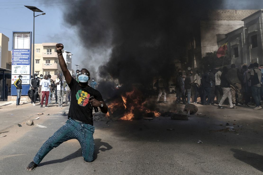 An opposition supporter reacts in front of a burning barricade during demonstrations called by the opposition parties in Dakar on February 4, 2024.