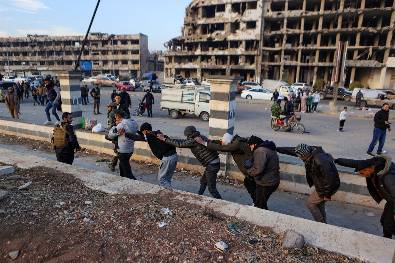 Rebel fighters parade detained members of the Syrian government's forces, who are wearing civilian clothing, in Homs.