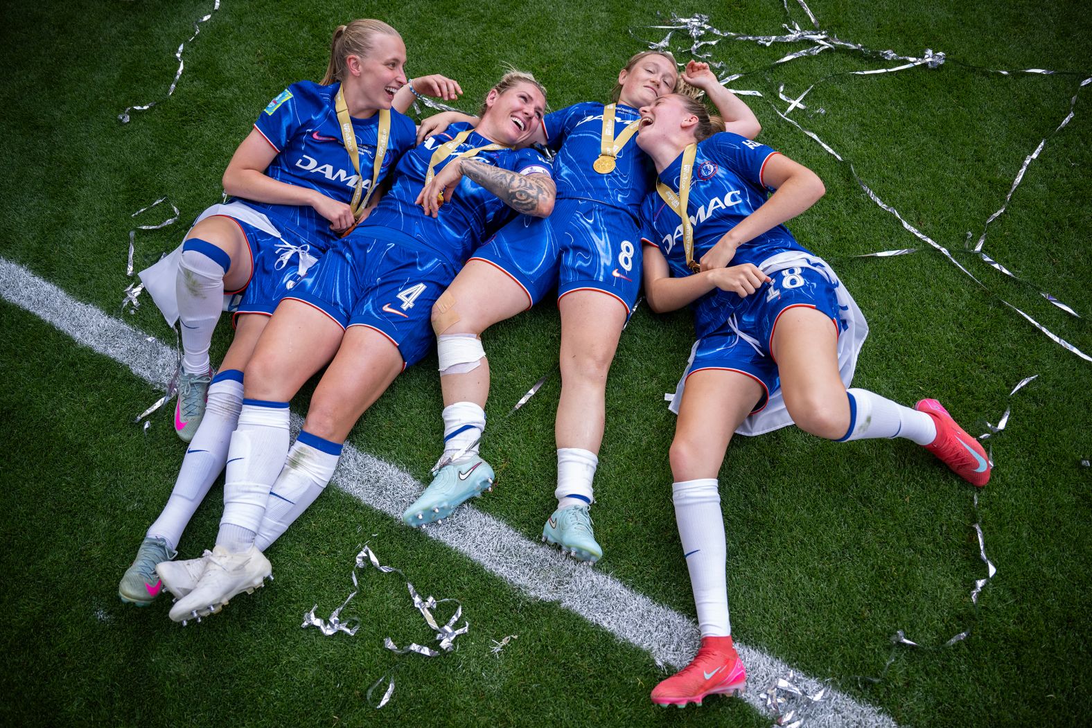 From left, Chelsea footballers Aggie Beever-Jones, Millie Bright, Erin Cuthbert and Wieke Kaptein celebrate after their <a href="https://www.cnn.com/2025/05/18/sport/chelsea-manchester-united-womens-fa-cup-spt">FA Cup final win</a> over Manchester United on Sunday, May 18. Chelsea also won the Women’s Super League and the League Cup this season.