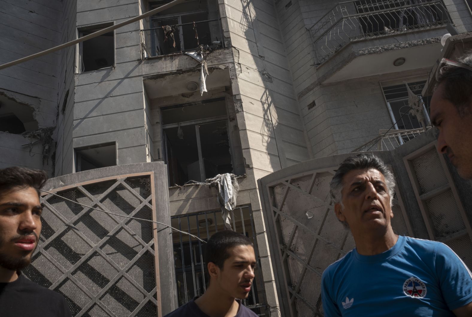 Men stand outside a destroyed residential building in Tehran on Friday.
