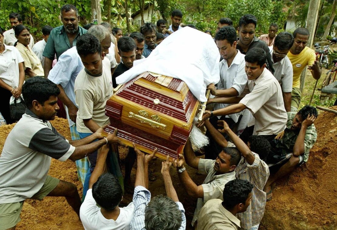 La gente baja un ataúd al suelo durante el funeral de dos víctimas del tsunami en Matara, Sri Lanka.