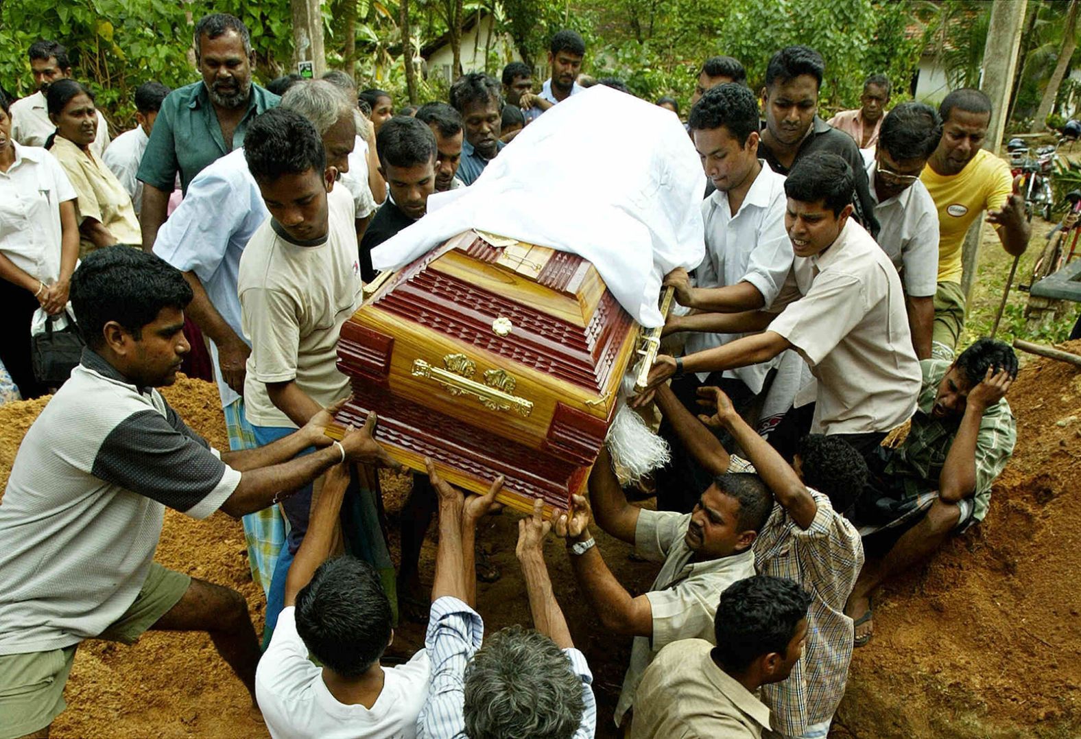 People lower a coffin into the ground during a funeral for two tsunami victims in Matara, Sri Lanka.