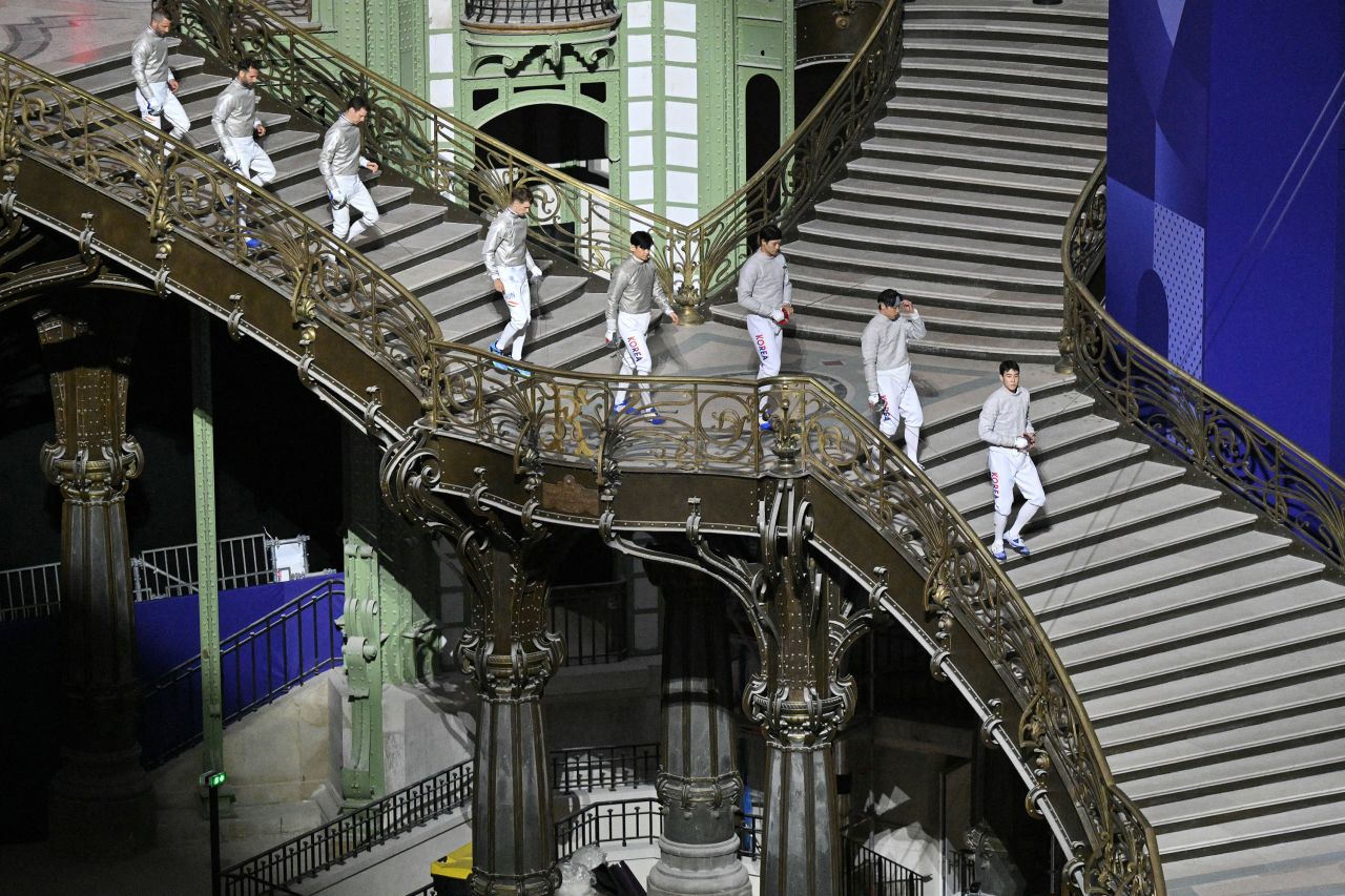 Team Hungary (L) and Team South Korea (R) walk down stairs as they arrive for the Men's Sabre Team Gold Medal bout at the Grand Palais on July 31.