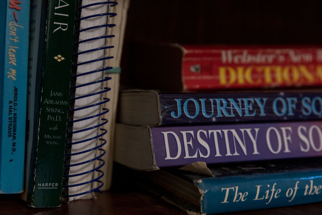 Books lie on a shelf in Scott Janssen’s home office.