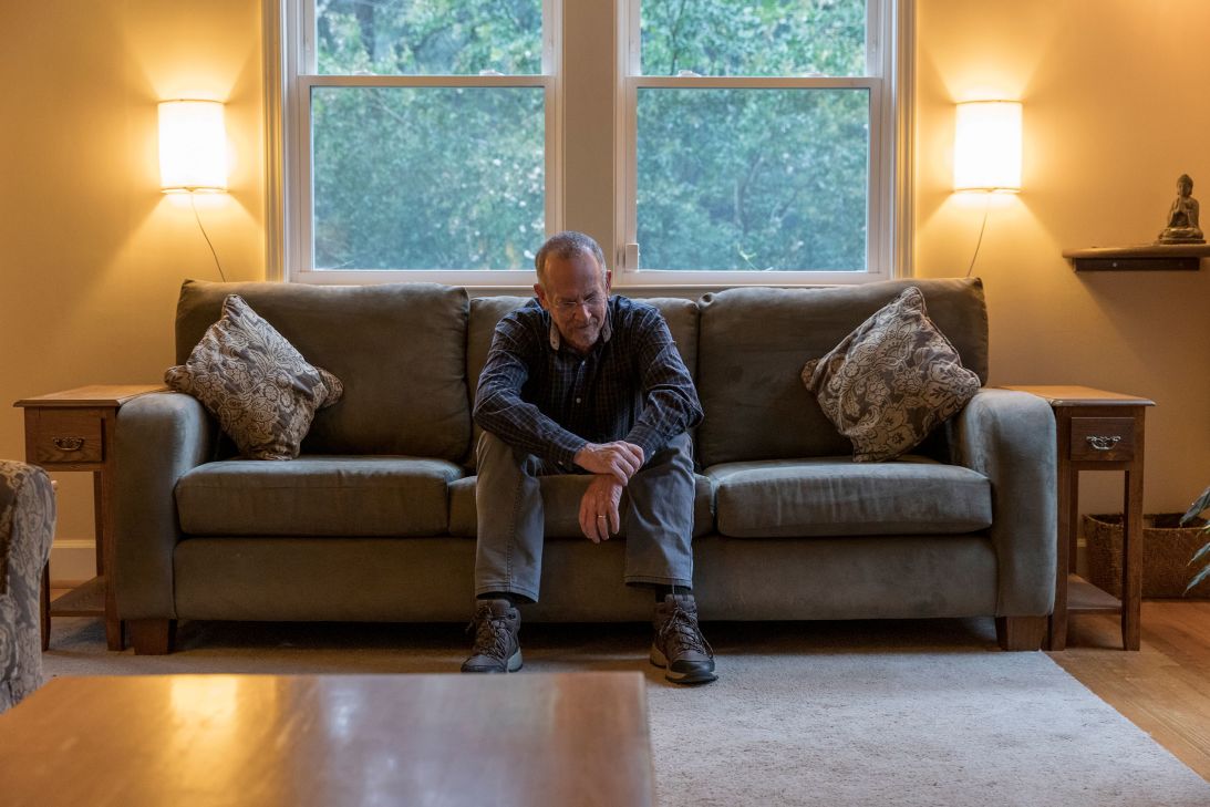 Scott Janssen rests on a couch in his home. “These (deathbed visitations) tend to be thematically consistent,” he says. “There’s a beginning, a middle and an end to the experience.