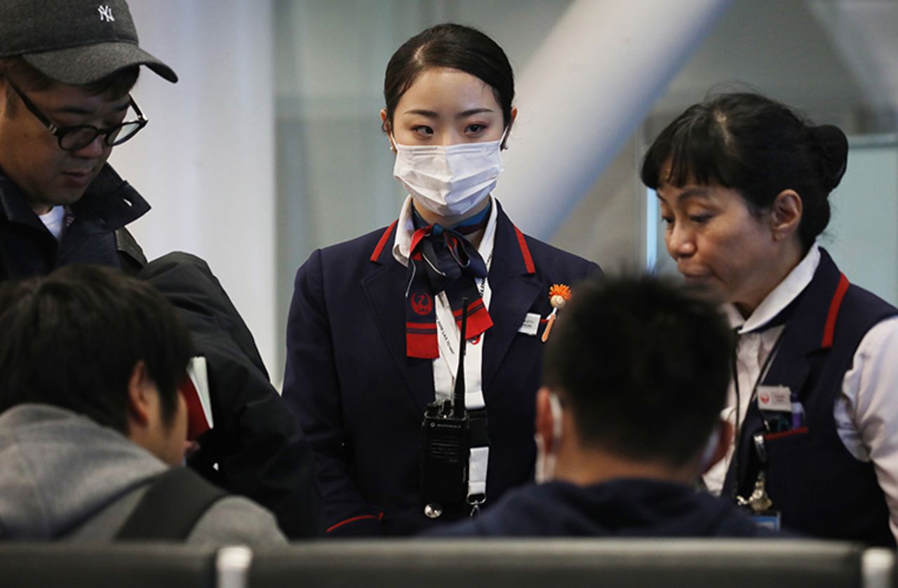  A Japan Airlines worker, center, wears a face mask while working inside a terminal at Los Angeles International Airport on January 23,  in Los Angeles, California, where screening was taking place for some incoming international passengers.