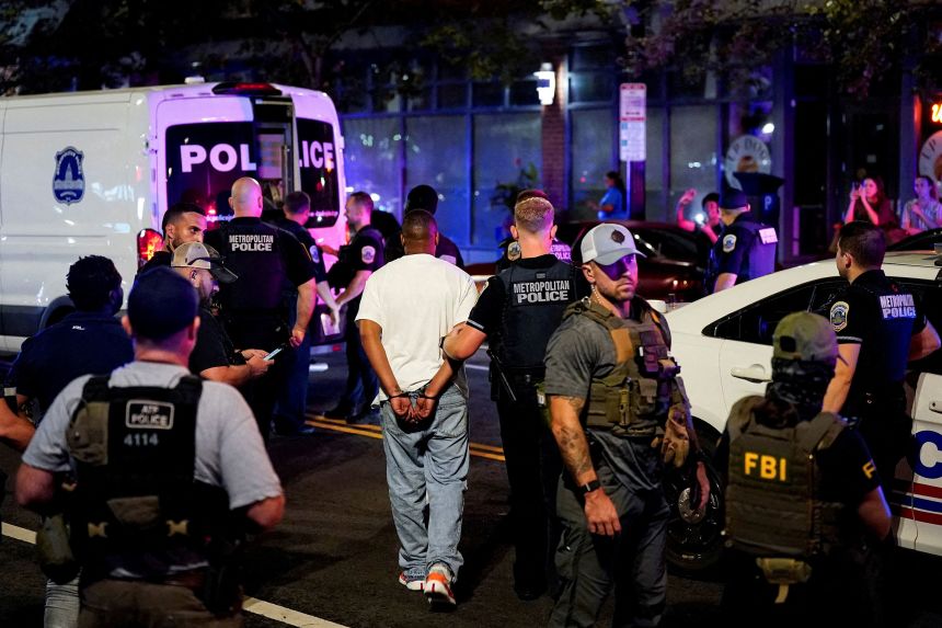 A detained man is led to a Metropolitan Police Department transport vehicle, during a traffic stop in Washington, DC, on August 17.