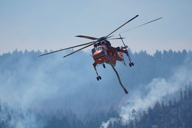 A helicopter heads in for a water drop as the Quarry wildfire burns in the foothills near the Ken Caryl Ranch development, southwest of Littleton, Colorado, on August 1, 2024.