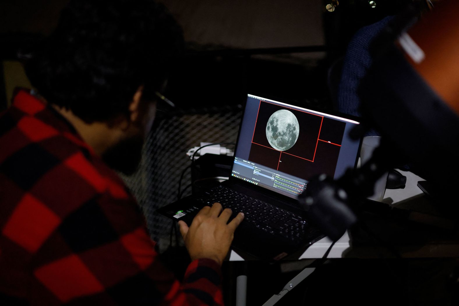 Scientists look at the moon, displayed on a screen, at the Foster Observatory in Santiago, Chile, prior to the lunar eclipse.