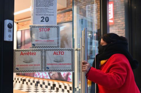 A person opens a door that has signs about masks in New York on January 8.