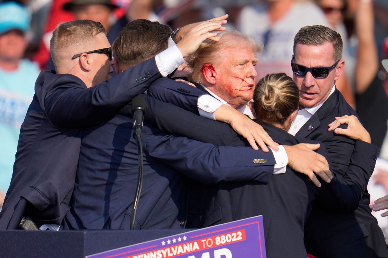 Former President Donald Trump is surrounded by US Secret Service agents as he is helped off the stage at a campaign rally in Butler, Pennsylvania on July 13. 