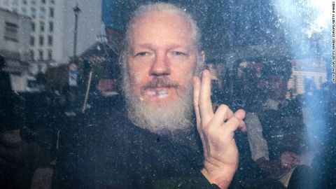 Julian Assange gestures to the media from a police vehicle on his arrival at Westminster Magistrates court on Thursday in London, England. 