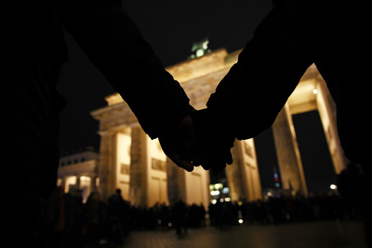 ?People hold hands during a vigil at the Brandenburg Gate to commemorate the victims of the Hanau shootings on Feb. 20 in Berlin.