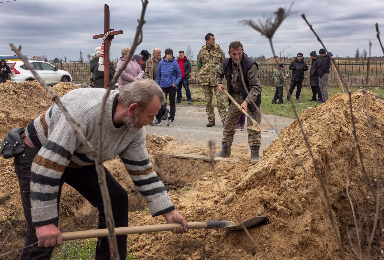 People shovel soil into an open grave in Buch on April 20 after Russian forces had retreated from the city.