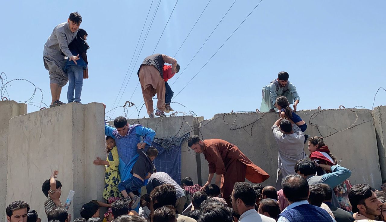 People struggle to cross the boundary wall of Kabul's Hamid Karzai international?airport on August 16.