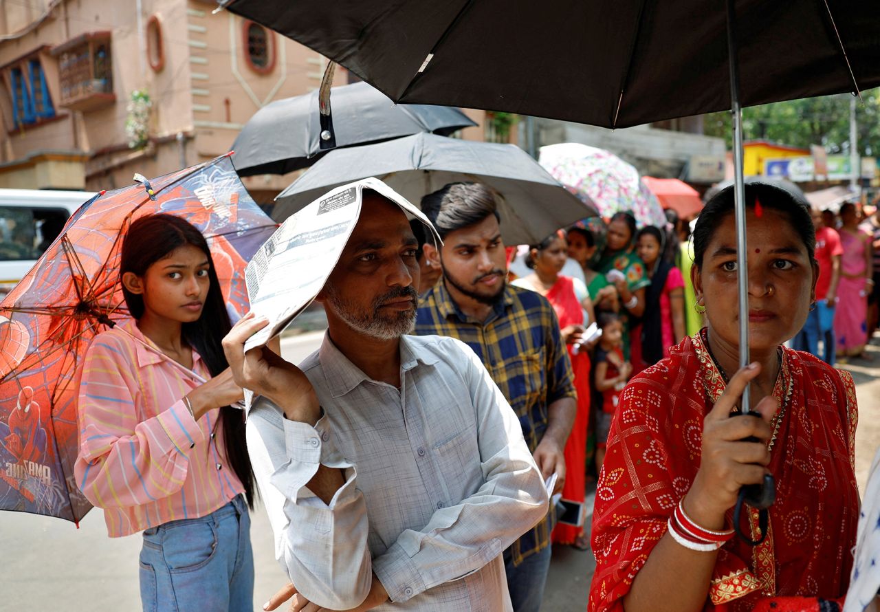 A man uses a newspaper as others use umbrellas to protect themselves from the heat as they wait to vote outside a polling station in the Howrah district of West Bengal, India, on May 20.