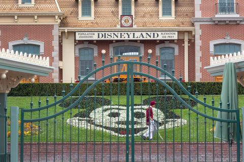 An employee cleans the grounds behind the closed gates of Disneyland Park in Anaheim, California, on March 14.
