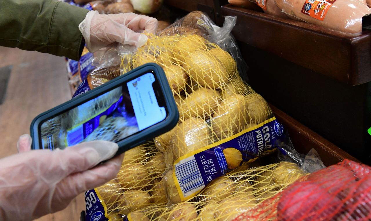 An Instacart employee uses her cellphone to scan barcodes showing proof of purchase for the customer while picking up groceries from a supermarket in North Hollywood, California, on March 19.