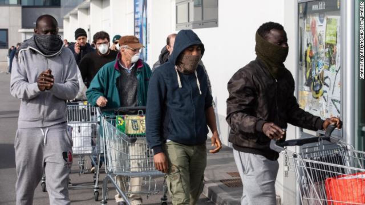 People wearing respiratory masks wait to be given a 10-minutes access to shop in a LIDL supermarket in groups of 20 people in Casalpusterlengo, Milan.