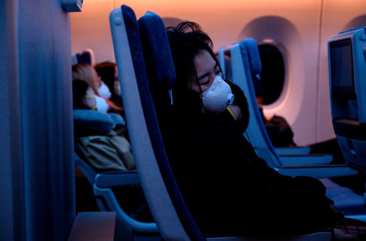 Passengers wearing protective face masks sleep on their flight to Shanghai on February 4.