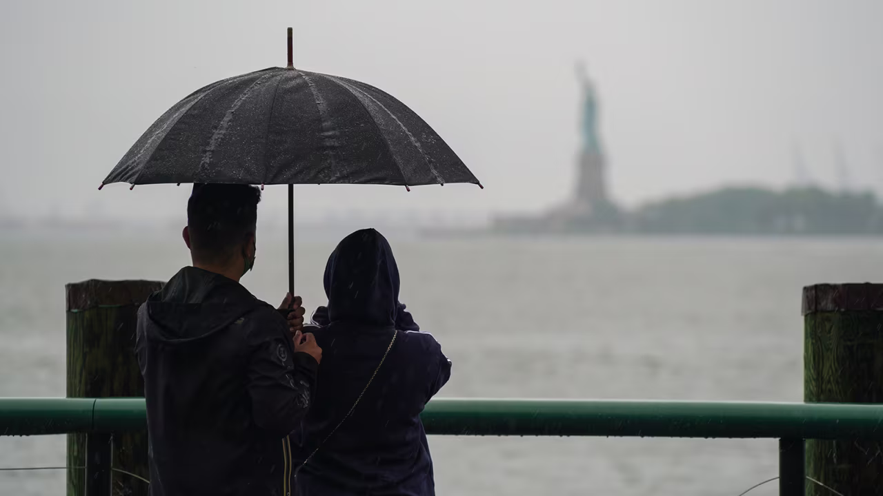 A couple take photos of the Statue of Liberty from Battery Park during Tropical Storm Henri on August 22, in New York City