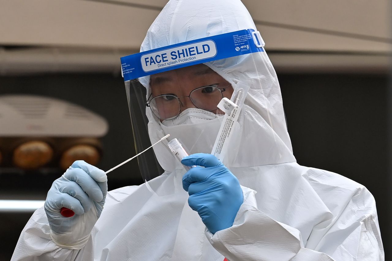 A medical staff member takes a swab from a visitor to test for Covid-19 outside the City Hall in Seoul on December 28. 