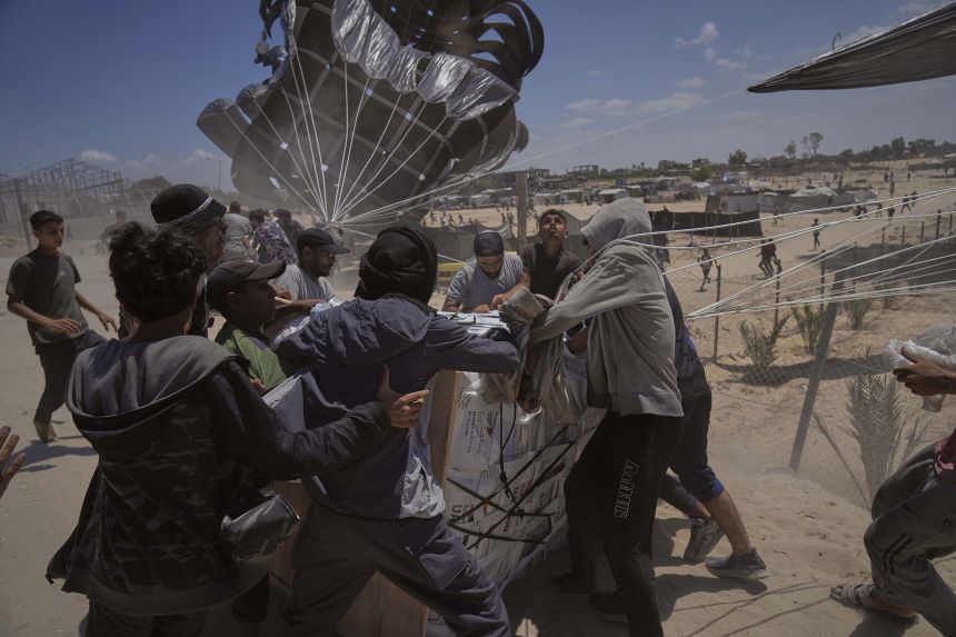 Palestinians rush to collect humanitarian aid airdropped by parachutes into Deir al-Balah, central Gaza Strip on Tuesday.