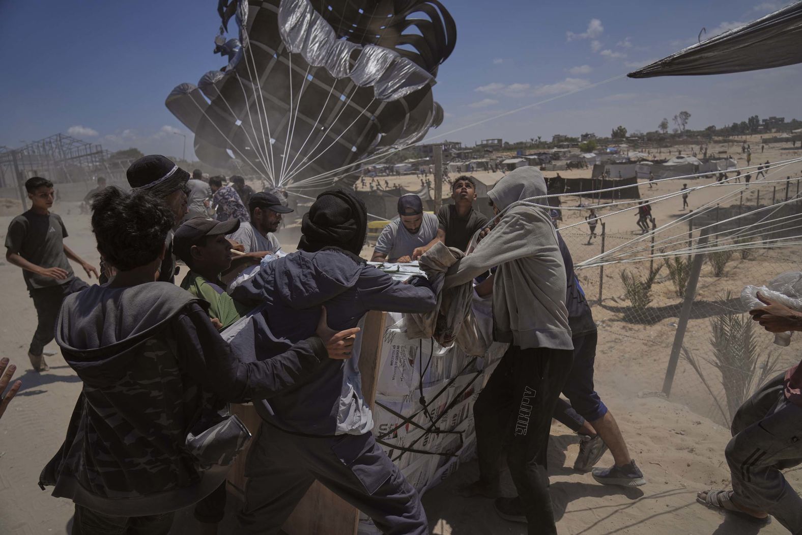 Palestinians rush to collect humanitarian aid airdropped by parachutes into Deir al-Balah in central Gaza on Tuesday, August 5.
