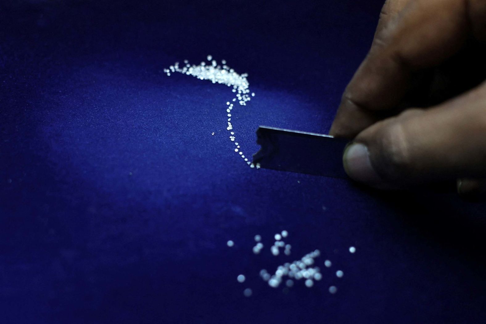 A worker sorts diamonds at a diamond processing facility in Ahmedabad, India, on Friday, August 8.