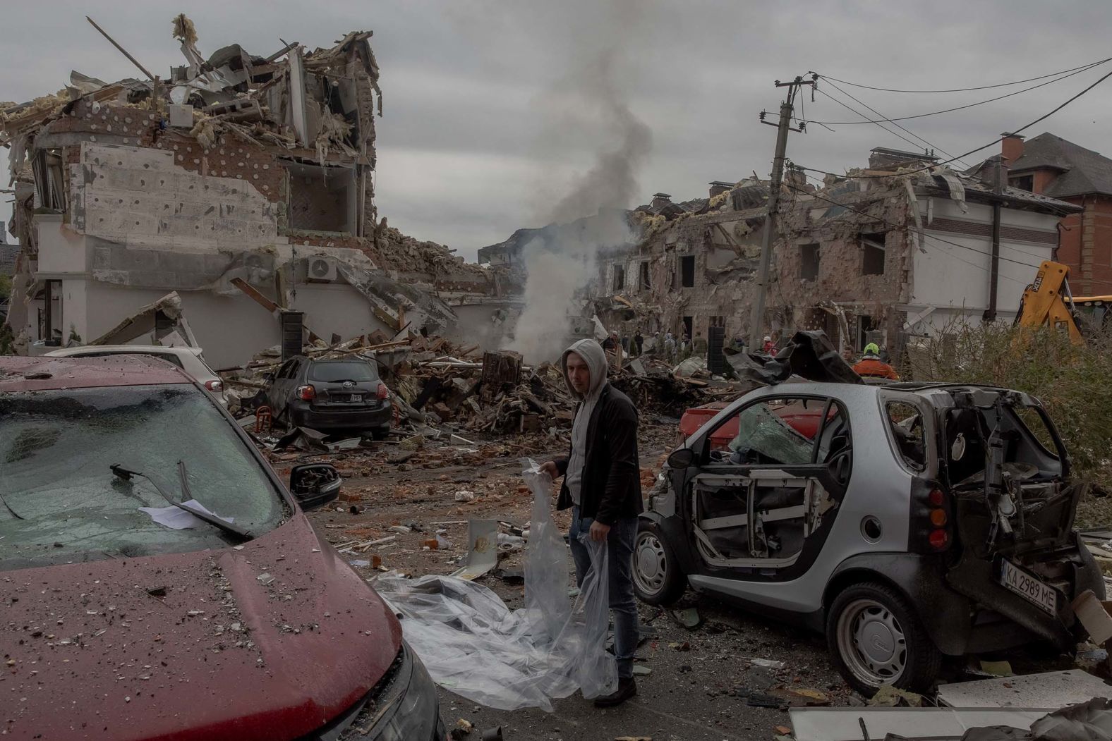 A resident prepares to cover a damaged car with a plastic sheet at the site of heavily damaged residential buildings following a Russian air strike on the outskirts of Kyiv, Ukraine, on Sunday, September 28.