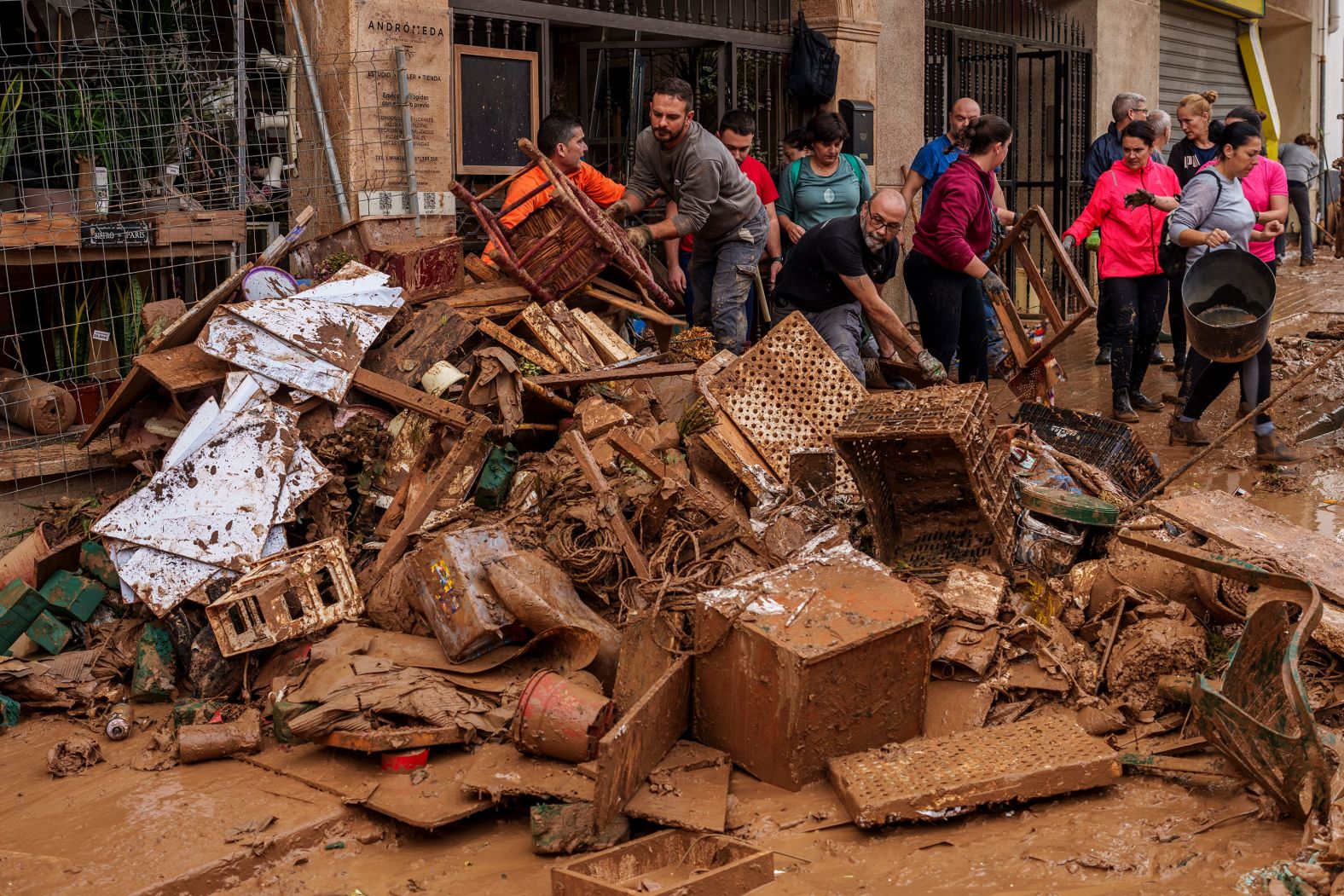 People clear debris from a shop in Chiva on Friday.