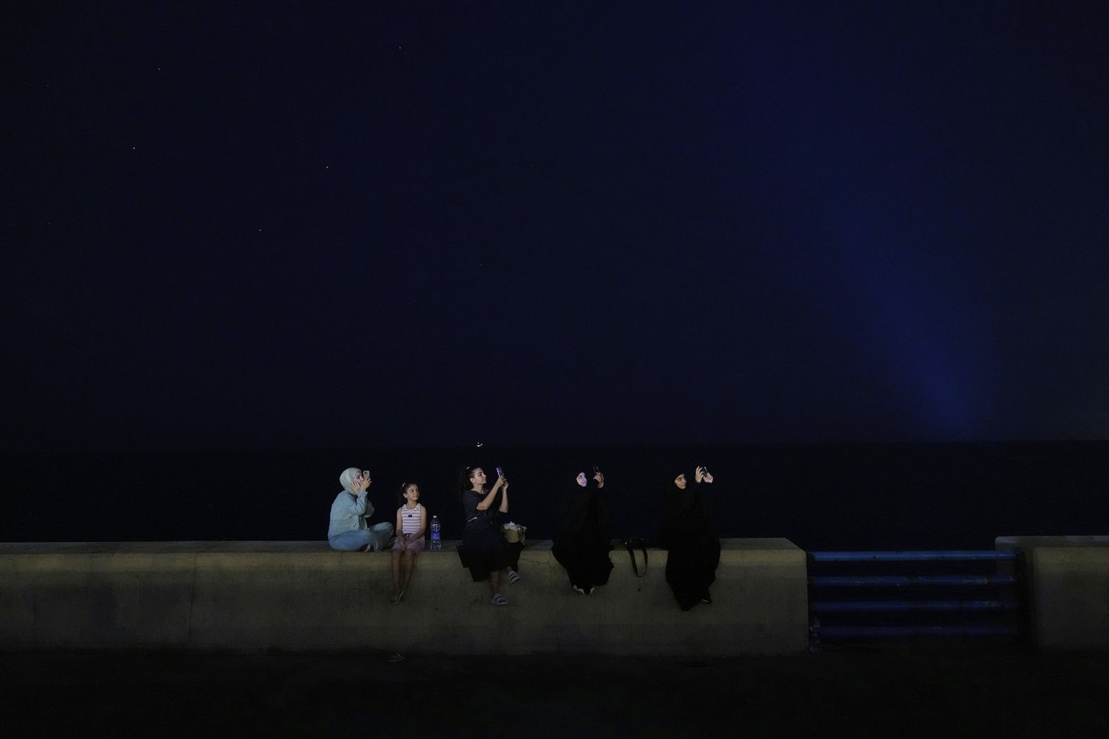 People take pictures of the lunar eclipse along a Mediterranean waterfront promenade in Beirut on Sunday.
