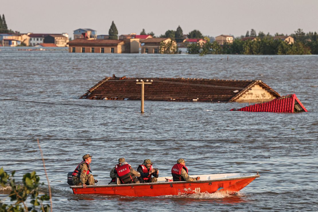 Rescue workers ride past the roof of an inundated house following a dam breach at Hunan province's Dongting Lake on July 7.