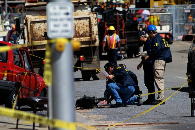 FBI and ATF agents search a car transmission thrown by the explosion.