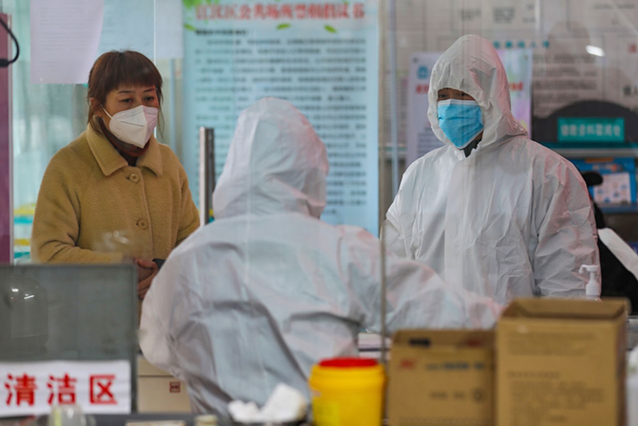 Medical workers in protective gear talk with a woman suspected of being ill at a community health station in Wuhan, China, on Monday, January 27.