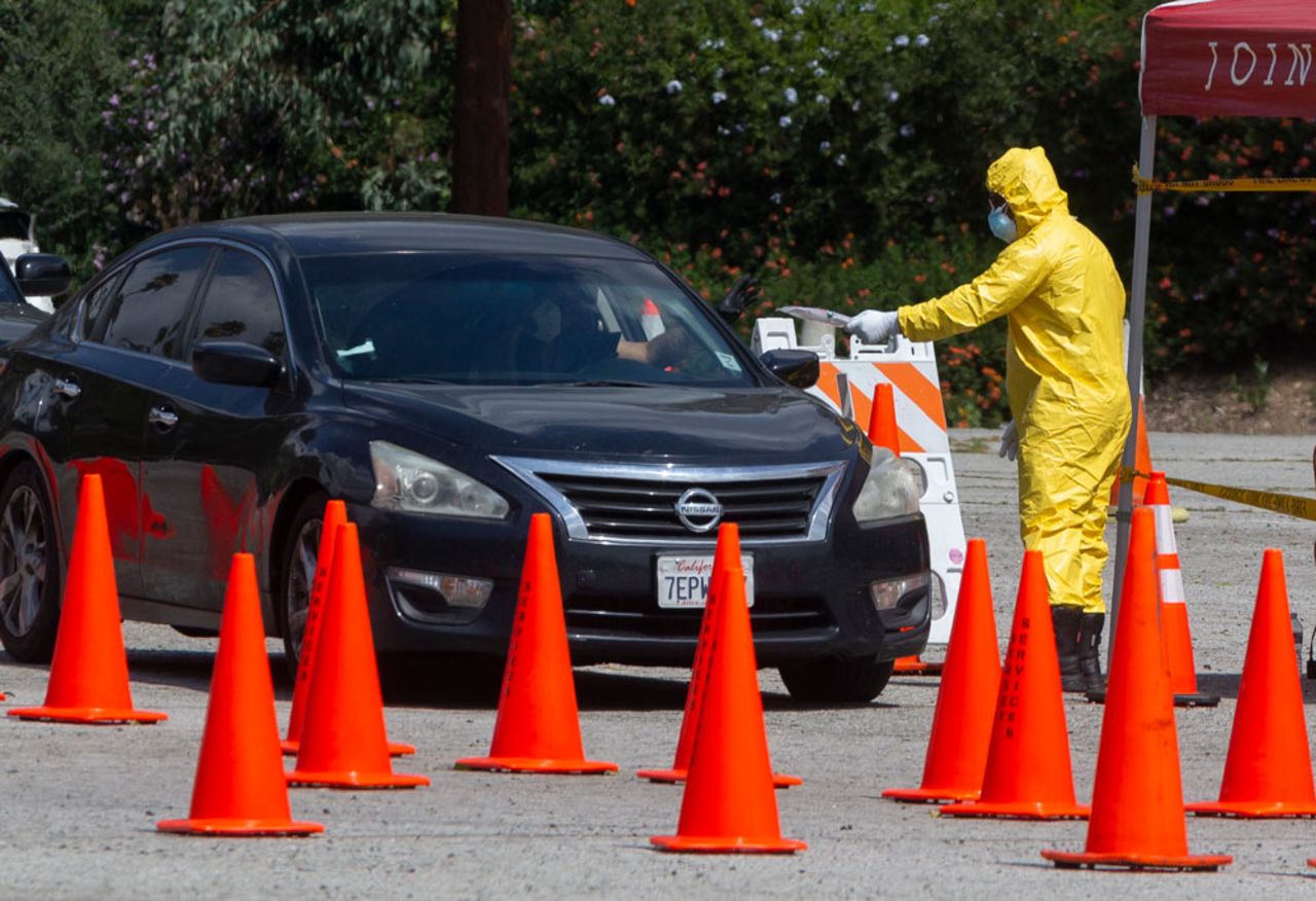 Los Angeles Fire Department officials deliver testing kits to waiting motorists at a coronavirus drive-up testing site in Elysian Park on Thursday, April 2.