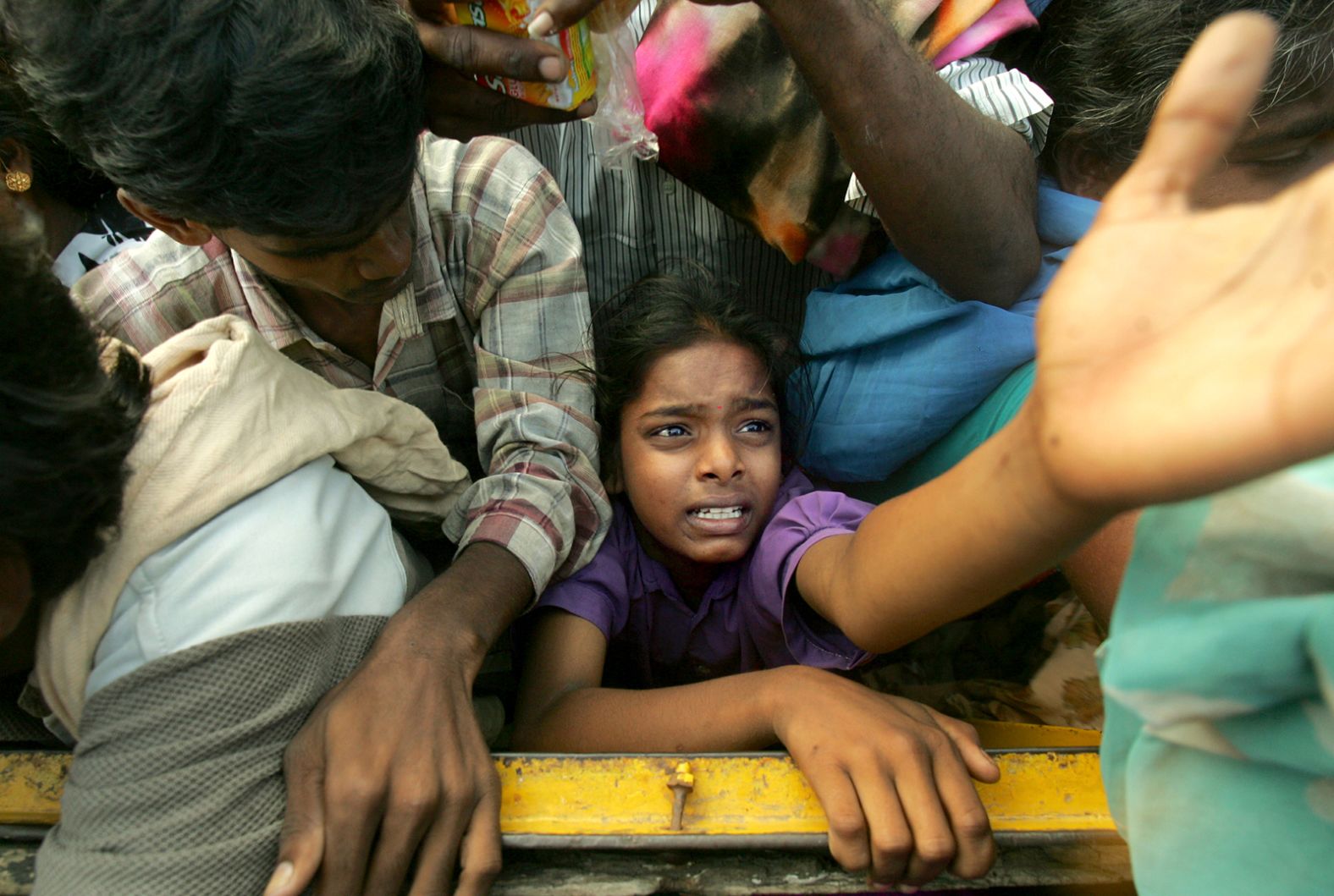 A young tsunami survivor reaches out for food and clothing that was being distributed by volunteer organizations in Cuddalore, India.