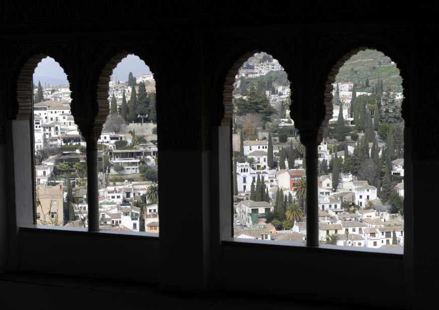 A view through pointed windows to the city of Granada. 