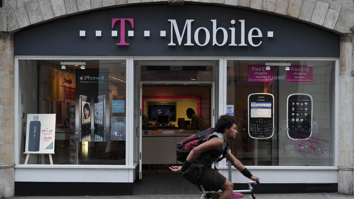 A biker rides past a T-Mobile store in London.