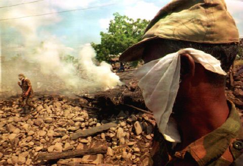 A soldier covers his face with a mask as he stands before a cremation fire in Mahahashtra state on October 02, 1993.