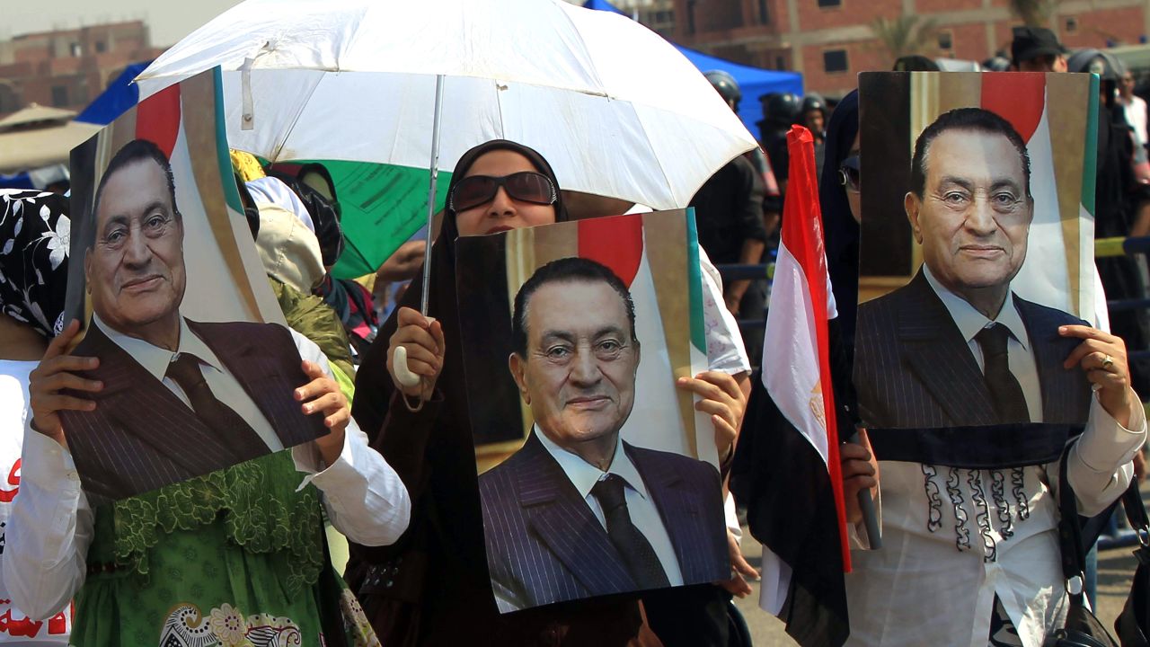 Supporters of former Egyptian president, Hosni Mubarak hold up posters of him outside the Cairo criminal courts on August 15. 