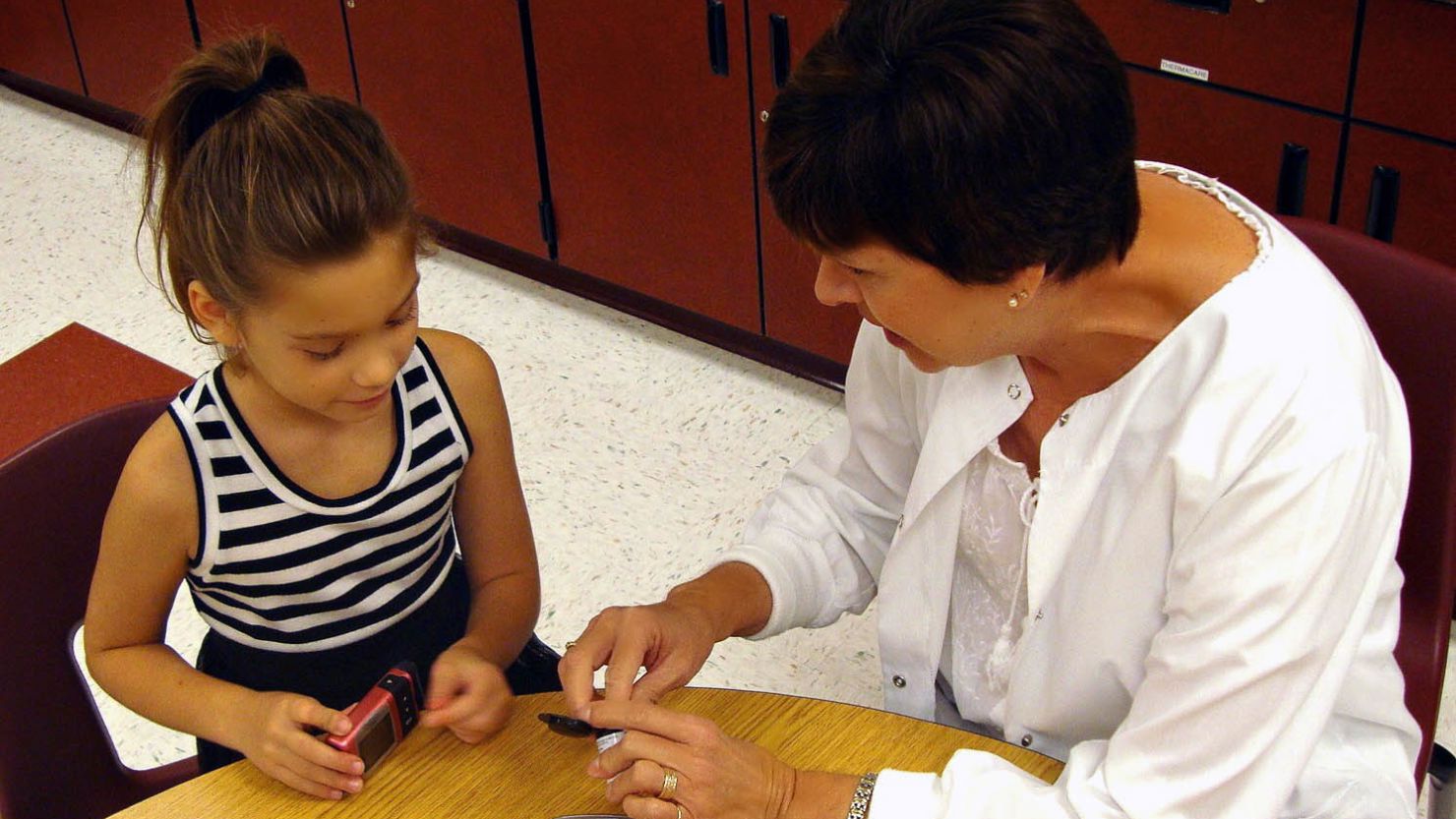 Adalyne Rose tests her blood glucose levels with the help of her school nurse, Carla Moore.