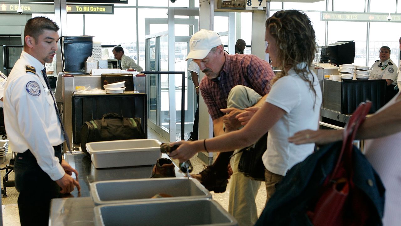 A passenger takes off his shoes at a security check-point at Dulles International Airport .