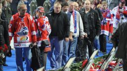 People mourn in front of the portraits of victims during a memorial ceremony for those killed in the Russian ice hockey team Lokomotiv Yaroslav plane crash at Arena-2000 the team's stadium in Yaroslavl on September 10, 2011