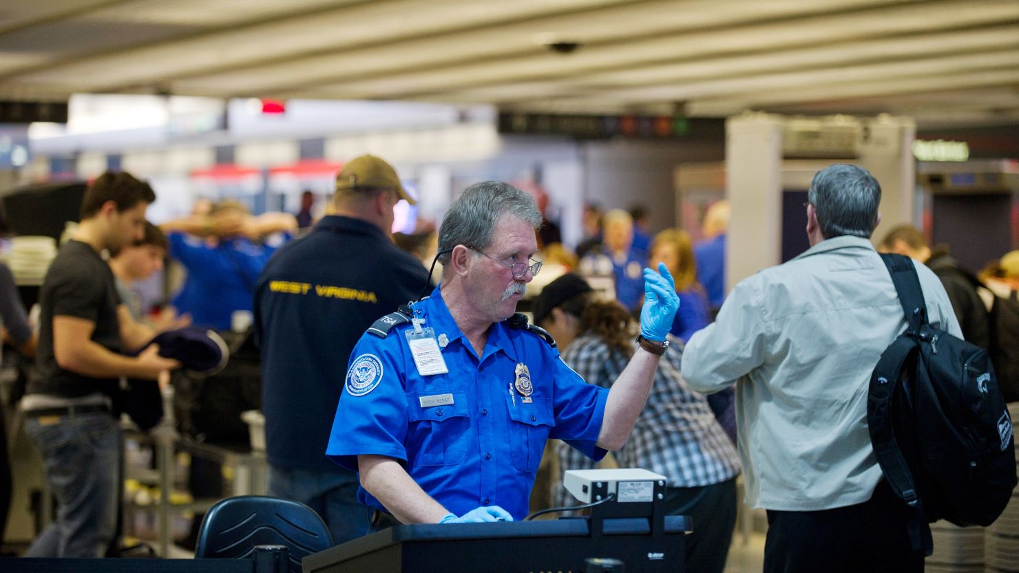 A Transportation Security Administration agent helps travelers move through security lines at Pittsburgh International Airport.