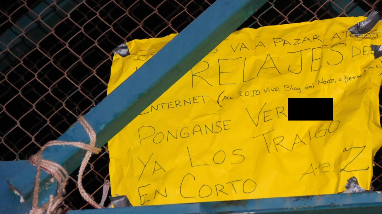 A sign near two bodies of people hung from a bridge in Nuevo Laredo contained messages threatening users of social media. The image has been edited for profanity.