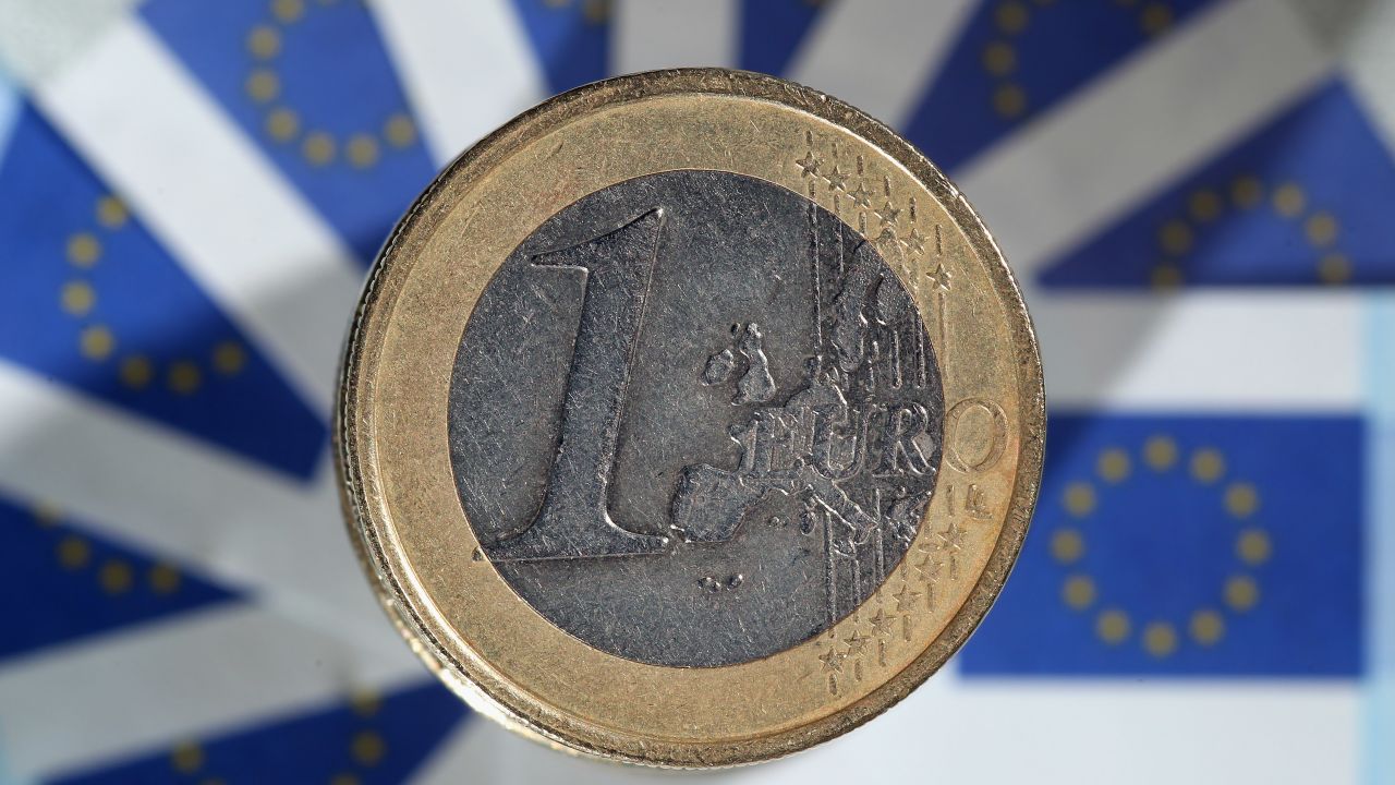 In this photo illustration a 1 euro coin sits on a display European Union flags.